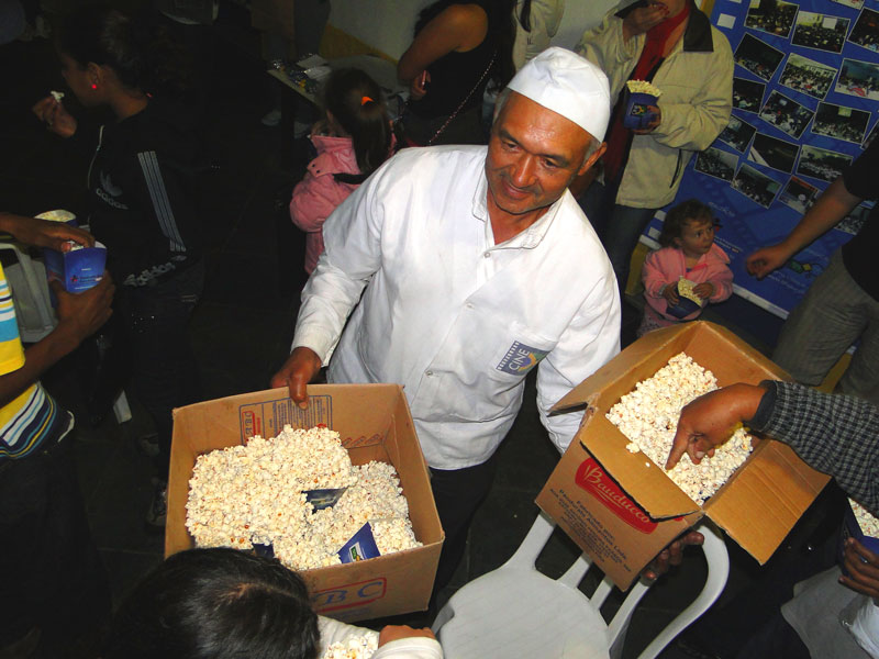 Seu Antônio Nascimento, o pipoqueiro oficial do Cine B, servindo a pipoca ao publico. Ele teve de deixar seu carrinho fora da Creche, ma deu seu jeitinho de ficar próximo do publico Seu Antônio Nascimento, o pipoqueiro oficial do Cine B, servindo a pipoca ao publico. Ele teve de deixar seu carrinho fora da Creche, ma deu seu jeitinho de ficar próximo do publico